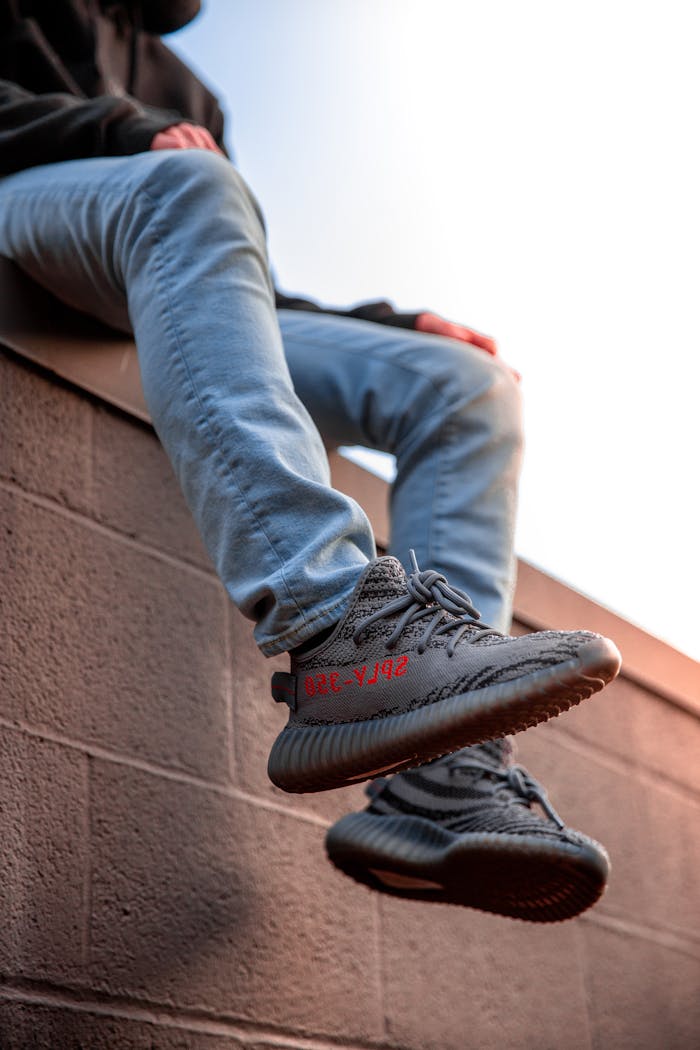 Stylish sneakers worn by a person sitting on a wall, showcasing timeless fashion.